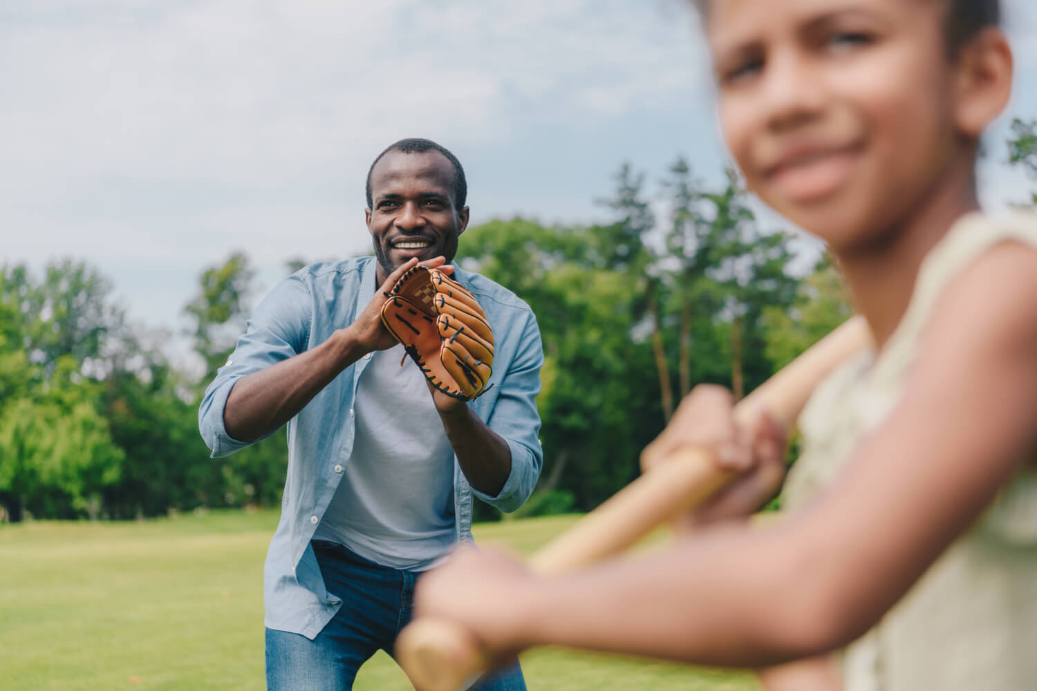 A middle aged black man playing baseball with his son after successfully receiving varicose vein treatment in Flint, Michigan