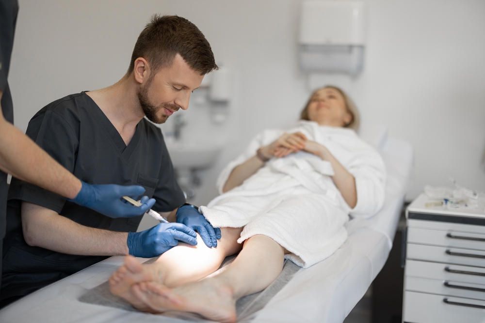 Phlebologist,Makes,Injections,Into,A,Vein,,Performing,Sclerotherapy,On,The Doctor performing sclerotherapy on a woman who has spider veins on her thighs