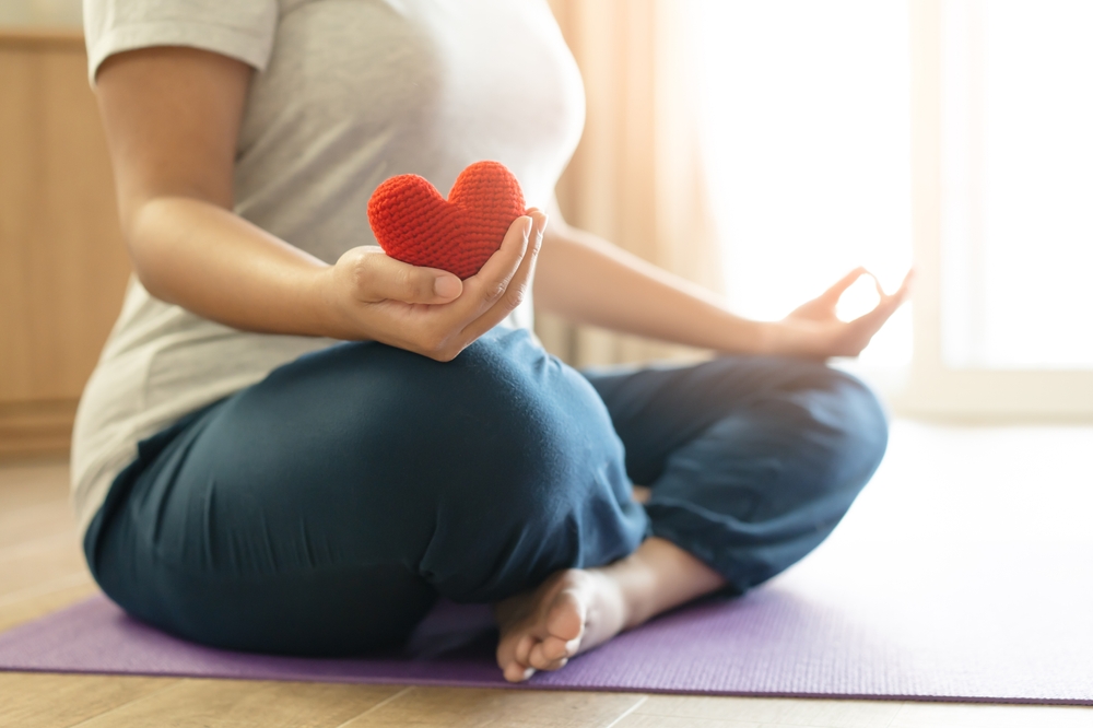 woman practicing yoga meditating for heart and cardiovascular health