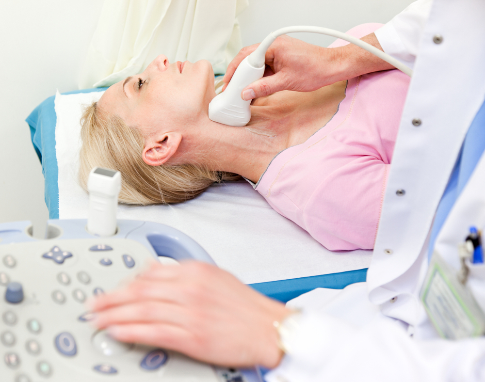 A woman getting the carotid artery in her neck scanned by an ultrasound.