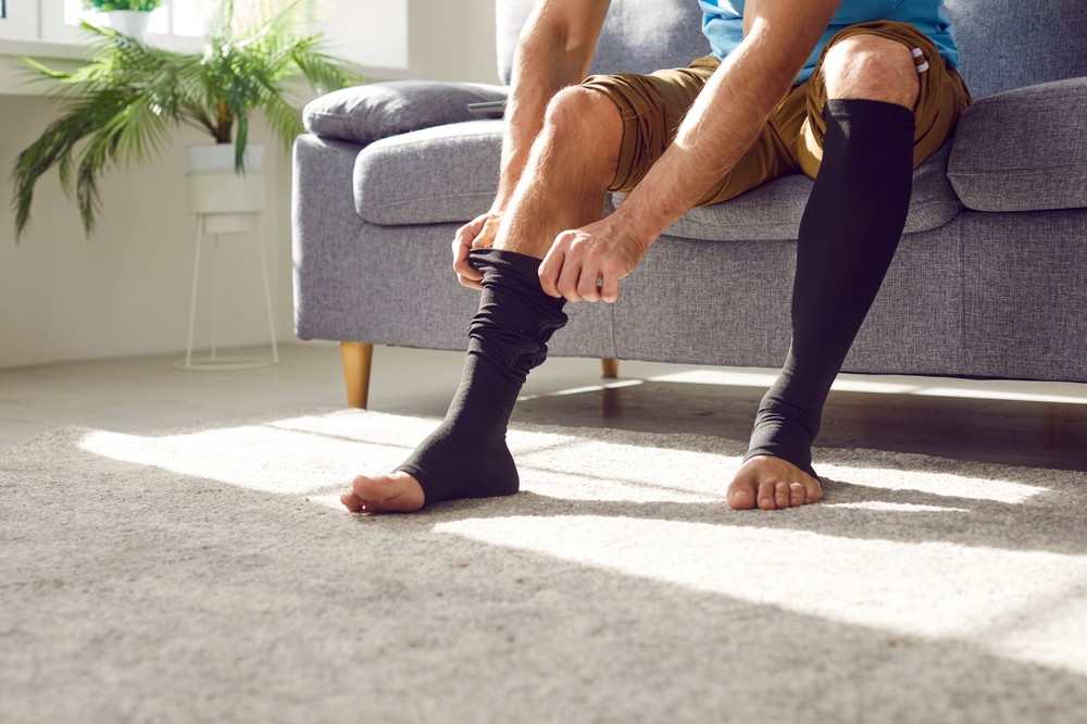 A man putting on compression socks.