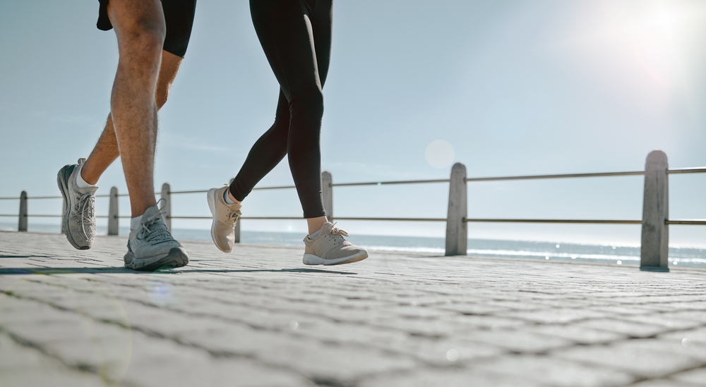People,,Legs,And,Running,At,The,Beach,For,Exercise,,Cardio Two people jogging together.