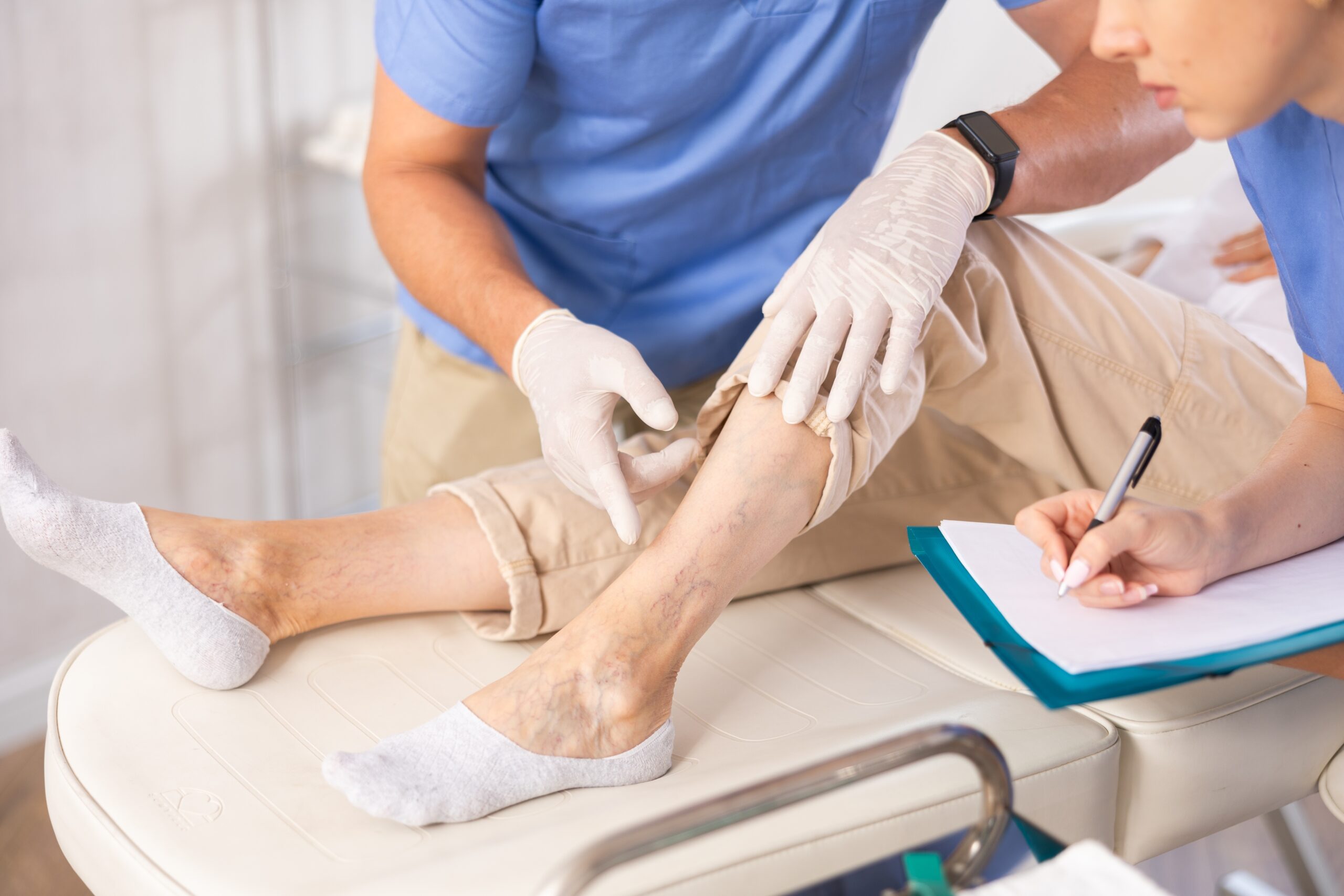 Doctor exaiming veins on patient's leg.